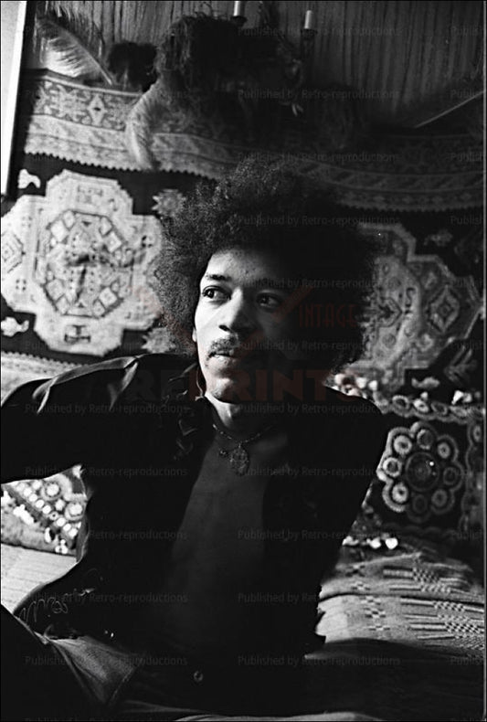 Photo of musician Jimi Hendrix sitting on a bed